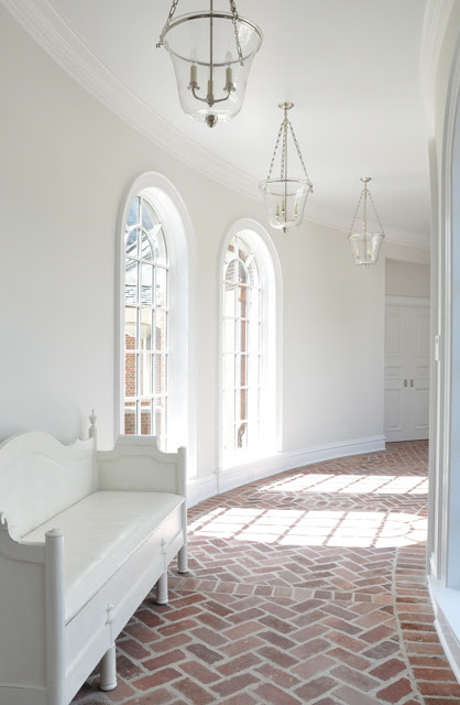 kathleen clements curved hallway hall arched windows brick floors herringbone pattern lanterns white walls cococozy